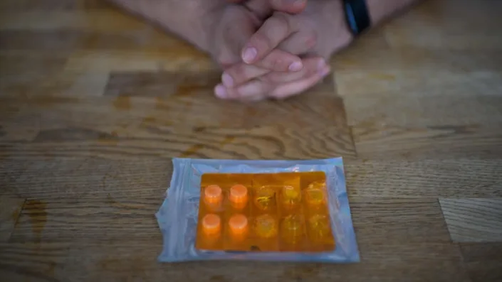 A pack of ketamine tablets is on a table in front of a patient’s hands.