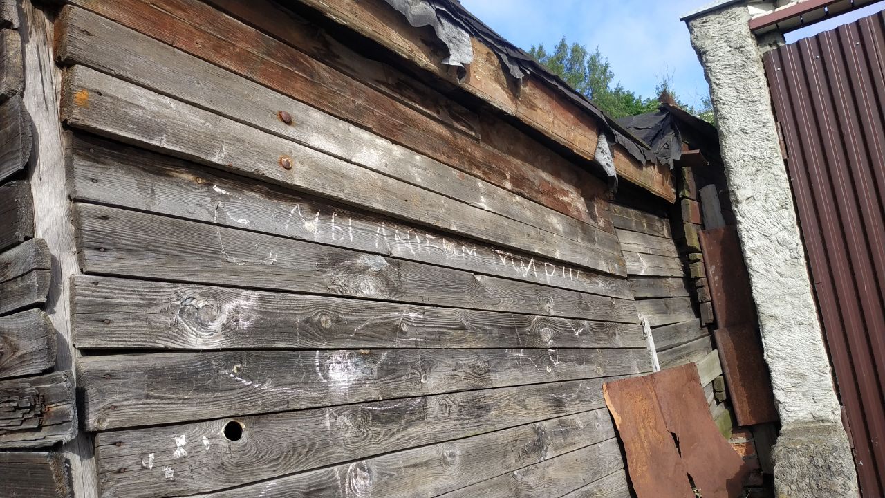 Натпись мелом на старом деревянном доме: “Мы любим мир”